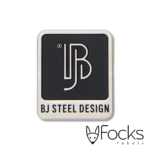 BJ Steel Design merklabel, gegoten zinklegering en vernikkeld, achtergrond ingelakt in mat zwart, achterzijde met structuur voor montage met kit.