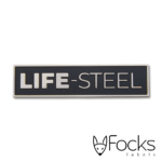Merklabel Life-Steel, gegoten zinklegering, glanzend vernikkeld, achtergrond verdiept en ingelakt in mat zwart, foamtape aan achterzijde.